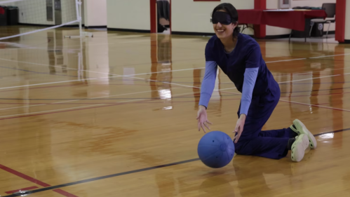 A goalball player wearing a blindfold passes the ball during a game on adaptive sports day 2022.