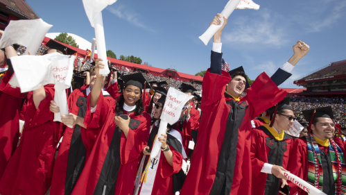 Students in caps and gowns cheering during 2023 commencement