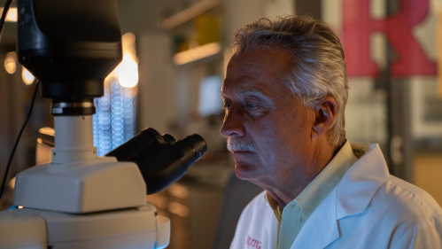 Asthma researcher Reynold Panettieri looks into a microscope in a lab.