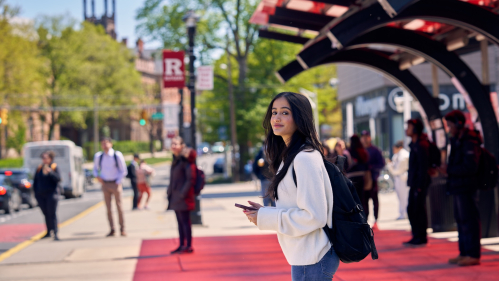 A student at the bus top on College Avenue