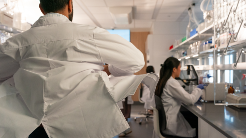 A researcher putting on his lab coat