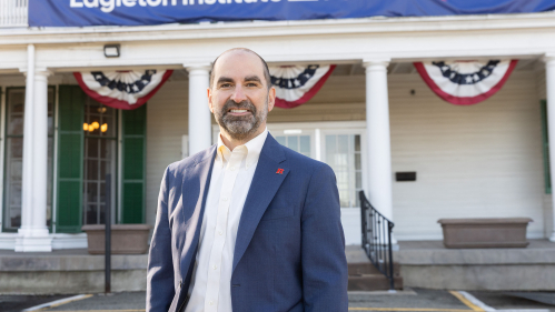 A man, Nick Longo, smiling in front of the Eagleton Institute of Politics