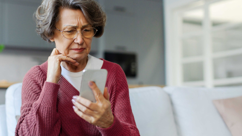 an older woman looking at her smartphone with a pensive look