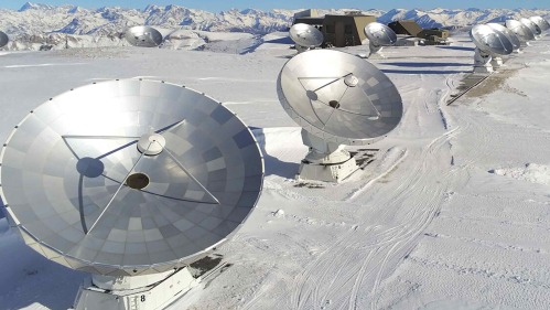 An array of telescopes on a snow-capped mountain.
