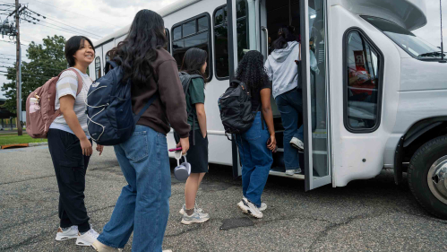 Students board a white shuttle bus