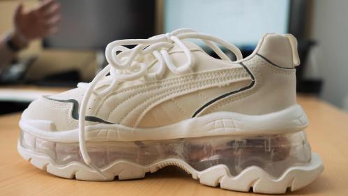A white sneaker with electronics in its nearly see-through heel.