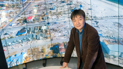 Jie Gongis stands in front of screens