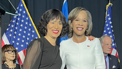 Two women standing in front of three American flags