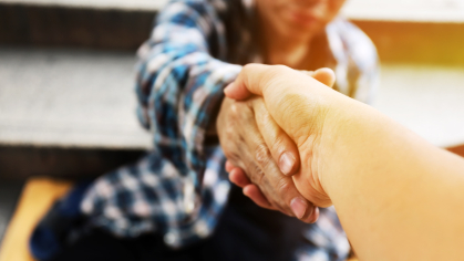 Close-up handshake of a homeless man receiving help from a person on the street