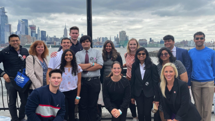 Students and faculty in the IDEA program posting in front of the New York City skyline at an event