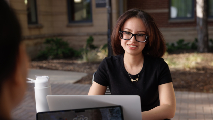 A student talking to a friend while on a laptop
