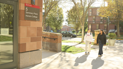 Two students walking into the Honors College building
