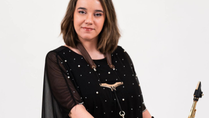 Kristin Field in a blowing black top holding a saxophone