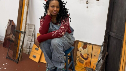 Sophia Yemisi Adeyemo sitting on a blue ladder in an art studio