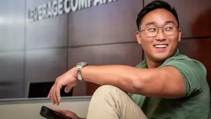 David Choi in a green shirt and khakis sitting in front of a wall