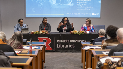 A panel of speakers in a desk in front of a room of people