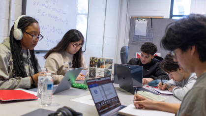 Students sitting at a table working on their laptops