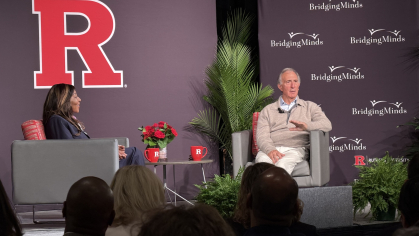 Chancellor Conway and Peter Seligmann sitting on a stage in front of a big red R