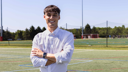 a Rutgers alumnus wearing business casual clothes on a soccer field