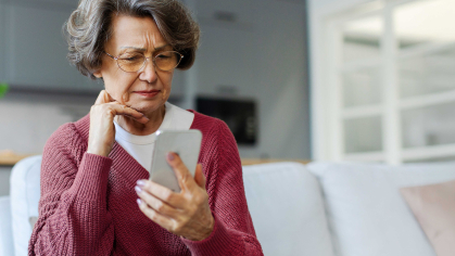 an older woman looking at her smartphone with a pensive look