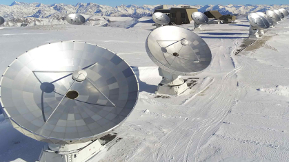 An array of telescopes on a snow-capped mountain.