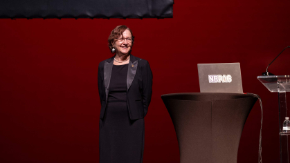 Woman standing on a stage next to a podium