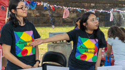 Zimmerli Mobile representatives Hanna Cherres (left) and Jessie Garcia interact with attendees during the Wash and Learn end-of-year celebration on June 9 outside the New Brunswick Public Schools office.