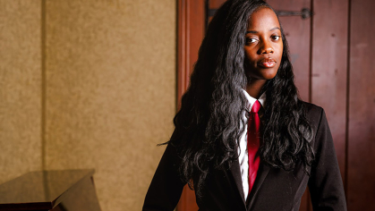 Rutgers senior Latisha Lubega stands next to a piano in a dramatically lit room.