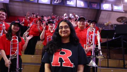 Business School student Sakshi Sowmya Aravind standing infront of the pep band at Jersey Mike's Arena