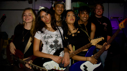 Members of the six-piece band Hanging Coats pose for the camera in a dark venue..