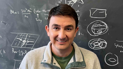 Nicolas Fernandez, a postdoctoral associate at Rutgers-New Brunswick, stands before a chalkboard marked with equations and sketches.