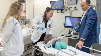 In a Rutgers simulation lab, Alex Bell (left) watches Amanda Sallemi provide air to a manikin under the guidance of Les Barta.