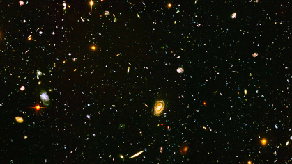 Hundreds of stars, some white dots, some larger red and orange orbs, against a black sky.