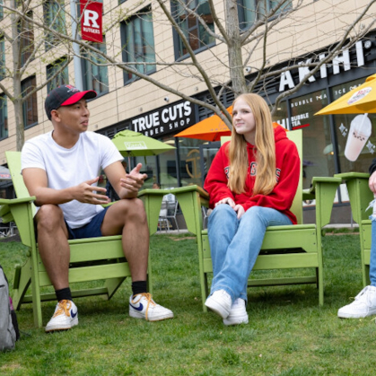 students seated in adirondack chairs chatting at The Yard