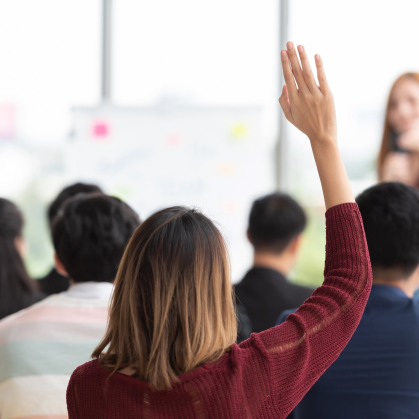 Female student raising her hand up in a classroom.