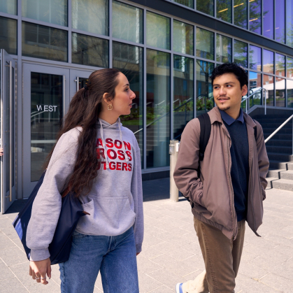 Roya Nock and Christopher Godoy walking outside of a building on campus