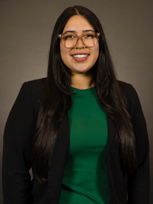 Melanie Ingles in a black blazer and green top and wearing glasses