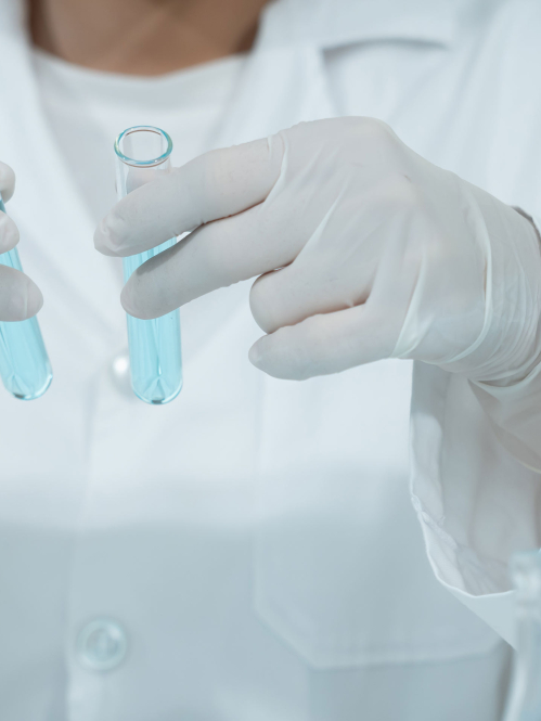 person in white lab coat working with test tubes. only the torso is visible
