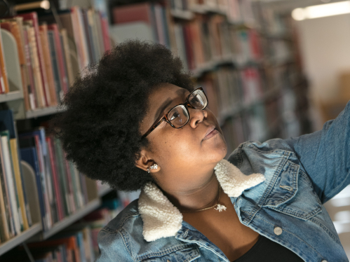 A student reaches for a book in Alexander Library