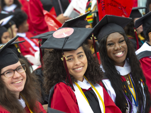 A group of three smiling college graduates wearing cap and gown
