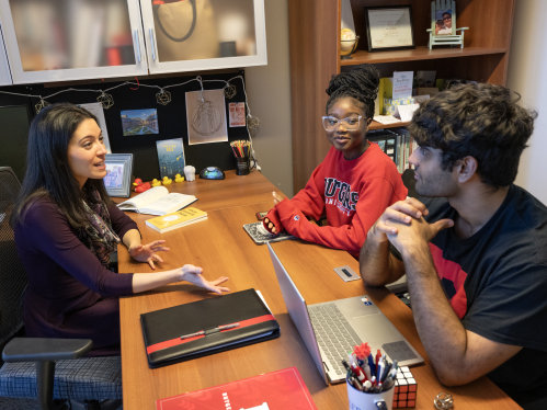 Advisor speaking with two students in an office