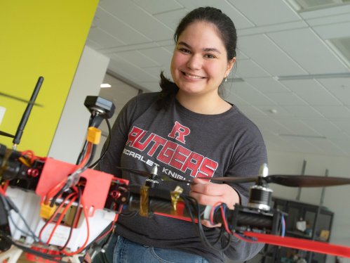 A student in the Weeks Lab smiling and working with a piece of machinery