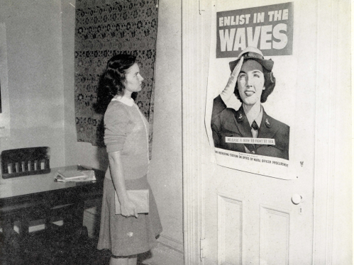 A female student looking at a poster for enlisting in the Women Accepted for Volunteer Emergency Service (WAVES)
