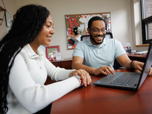 A student and an academic advisor looking at a laptop