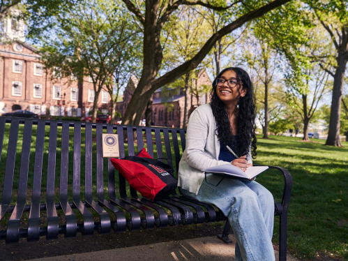 Student, Isha Parikh, sitting on a bench and writing