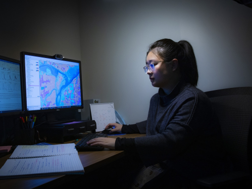 Research Associate Yifan Wang looking at maps and data on a computer