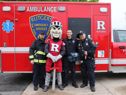 Members of Emergency Services posing with the Scarlet Knight at Rutgers Day