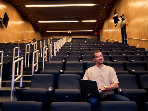 Aldemar Villanueva Jr. RBS’27 sitting in a lecture hall on his laptop