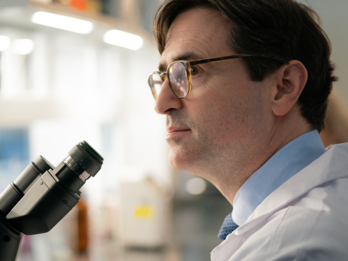 Dr. Christian Hinrichs in a research lab looking at a microscope