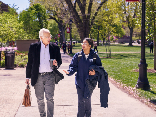 A student and professor walking and talking along Voorhees Mall